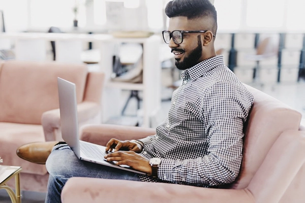 A smiling Indian SNHU student uses his laptop to study a degree online.